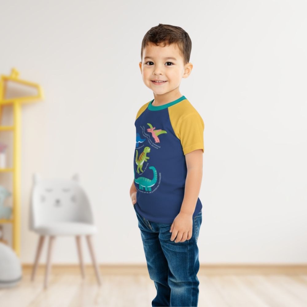 Child wearing a blue and yellow shirt with dinosaur designs indoors.