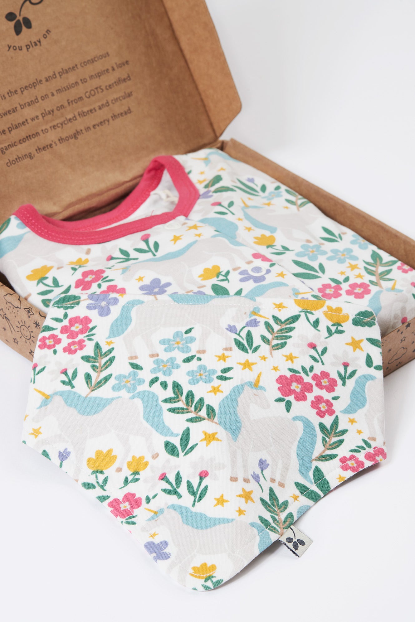 Organic cotton baby clothes with floral and unicorn pattern on a cardboard box