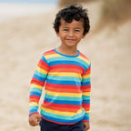 Child wearing a rainbow striped shirt on a beach