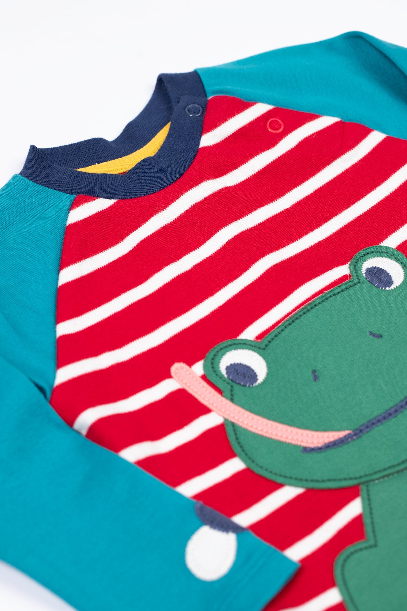 Children's outfit with red and white striped bib and green dinosaur design on a blue background