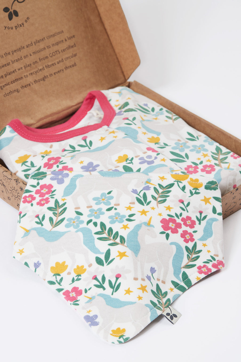 Baby romper with floral and dinosaur pattern on a cardboard box