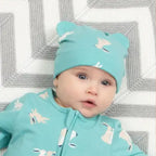 Baby wearing a matching turquoise outfit with animal patterns on a textured surface