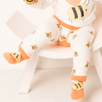 Child wearing a white outfit with bee designs on a white background