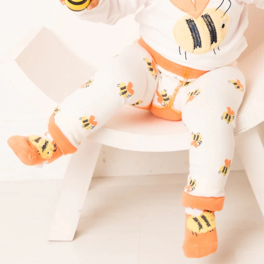 Child wearing a white outfit with bee designs on a white background