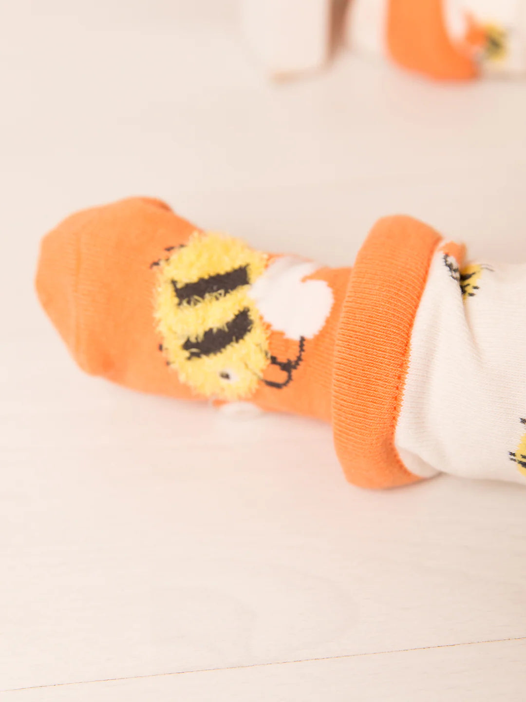 Orange socks with lion design on a light background
