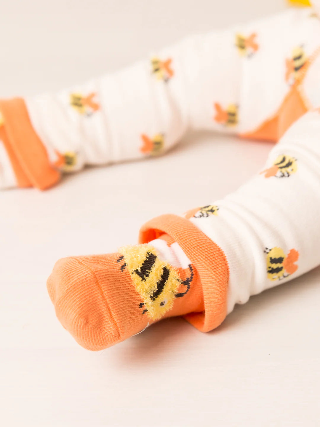 Baby socks with orange and white pattern on a light background