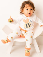 Child wearing a white outfit with bee designs on a white background