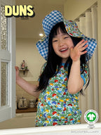 Child wearing a colorful apron and checkered hat in a kitchen, with DUNS Sweden branding.