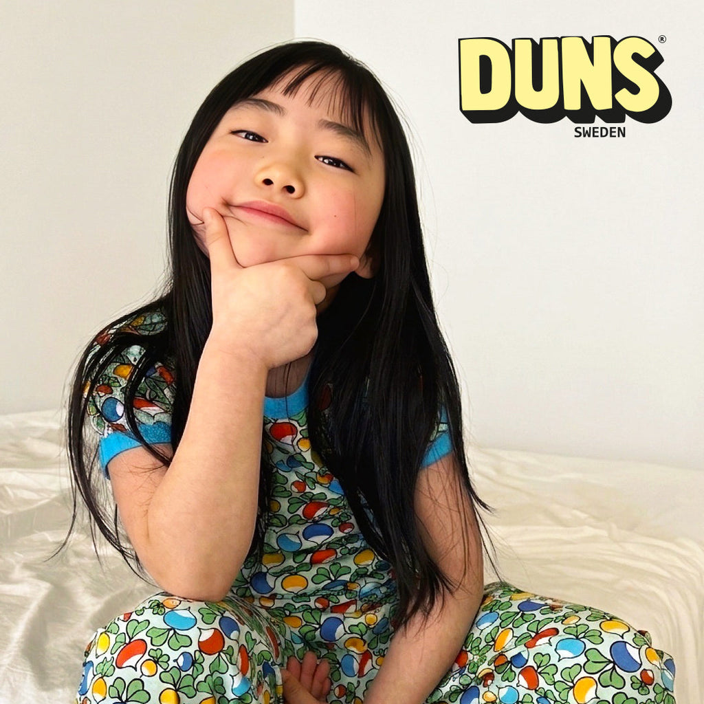 Child wearing a colorful outfit with Duns Sweden branding in the background