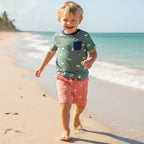 Child walking on a sandy beach with ocean and sky in the background