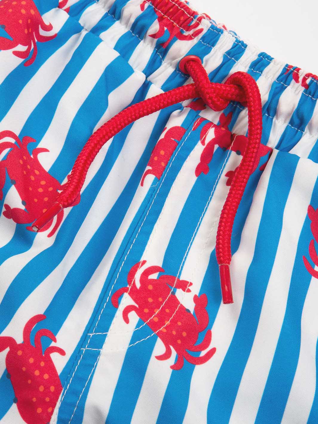 Blue and white striped swim shorts with red crab pattern and red drawstring.