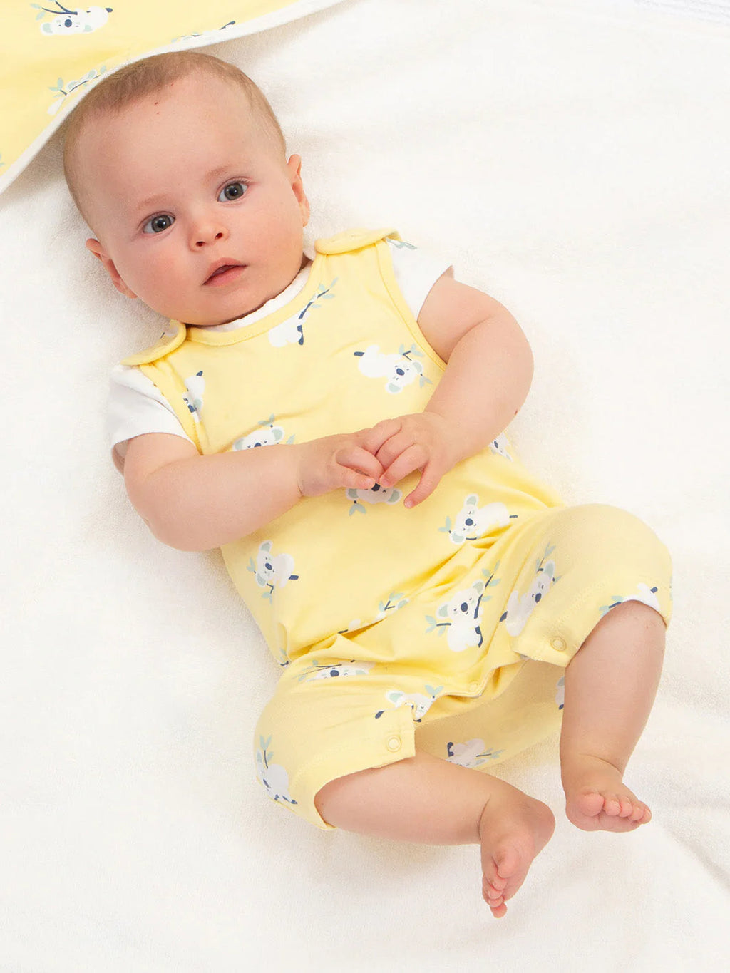 Baby wearing a yellow outfit with animal patterns on a white background