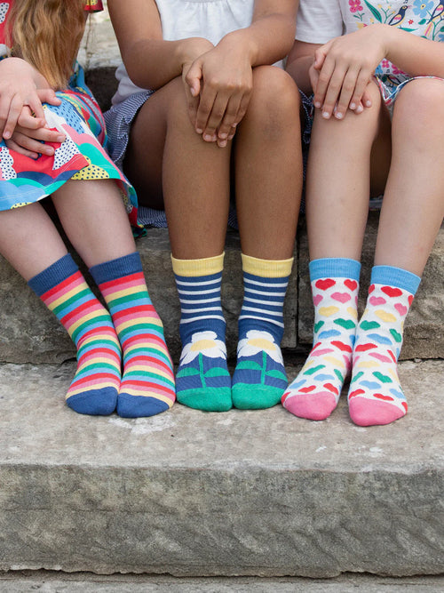 Four children wearing colorful socks sitting on a stone step.
