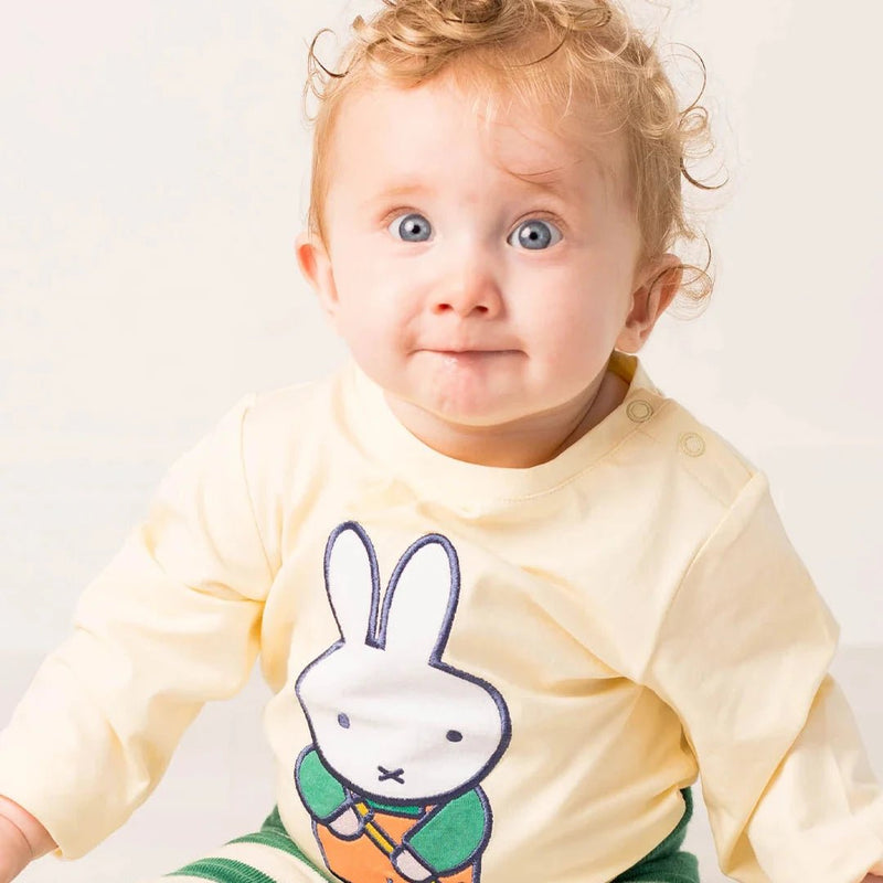 Baby wearing a yellow outfit with a cartoon character on a white background