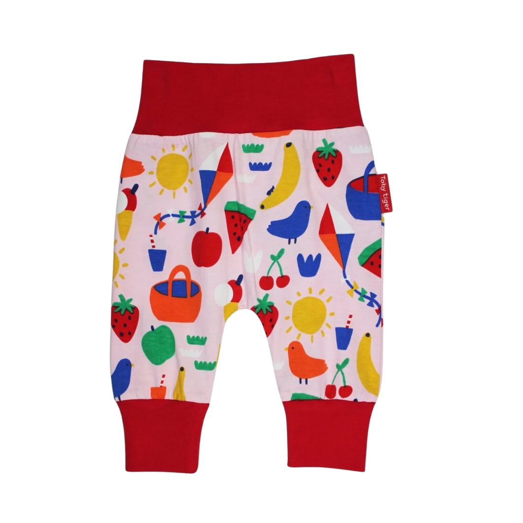 Colorful children's pants with a pattern of fruits, vegetables, and animals on a white background.