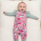 Baby lying on a chevron-patterned rug wearing a pink floral onesie.