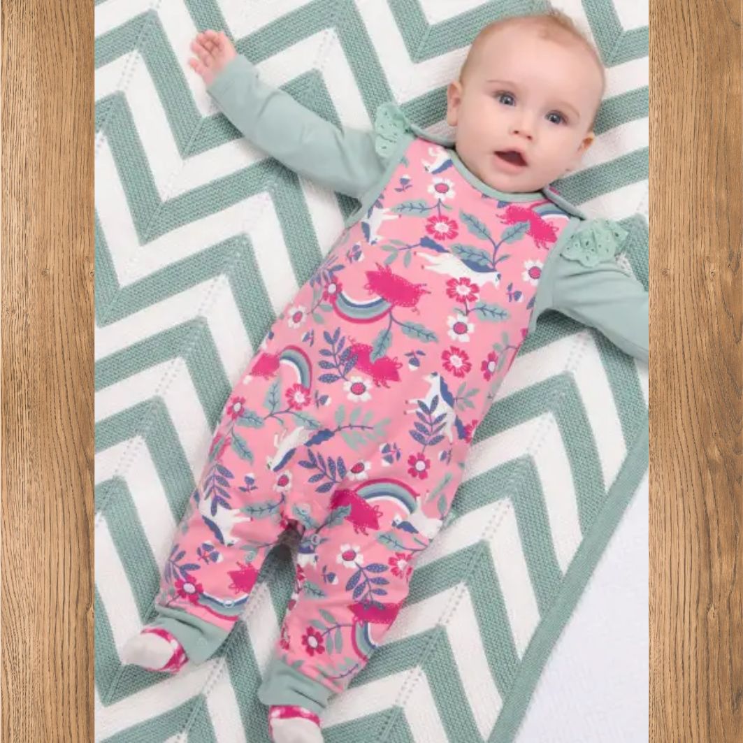 Baby lying on a chevron-patterned rug wearing a pink floral onesie.