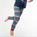 Child wearing a colorful outfit with a dinosaur design on a plain background
