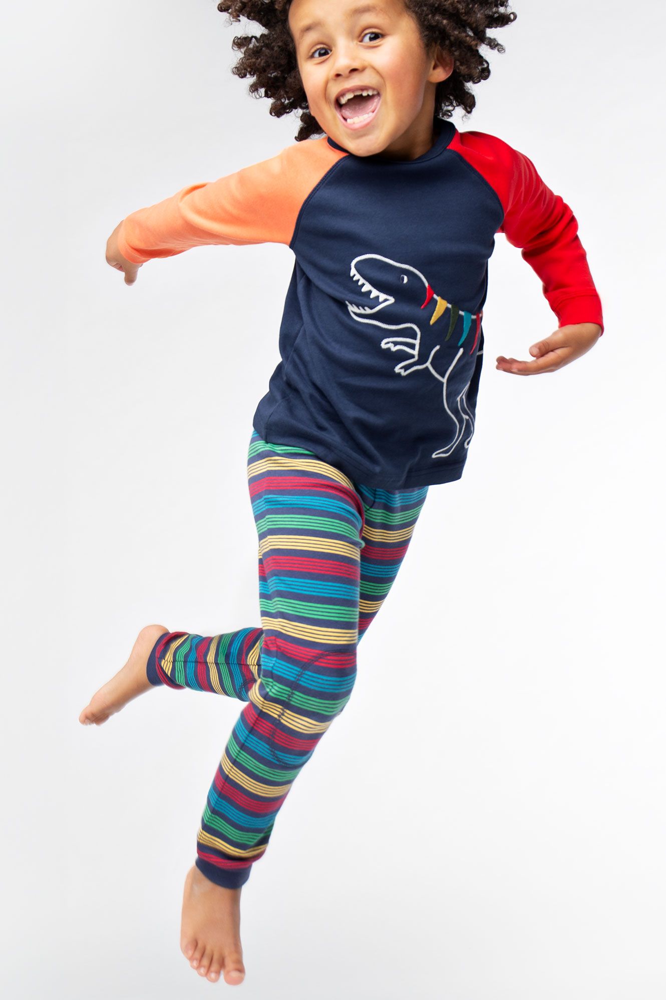 Child wearing a colorful outfit with a dinosaur design on a plain background