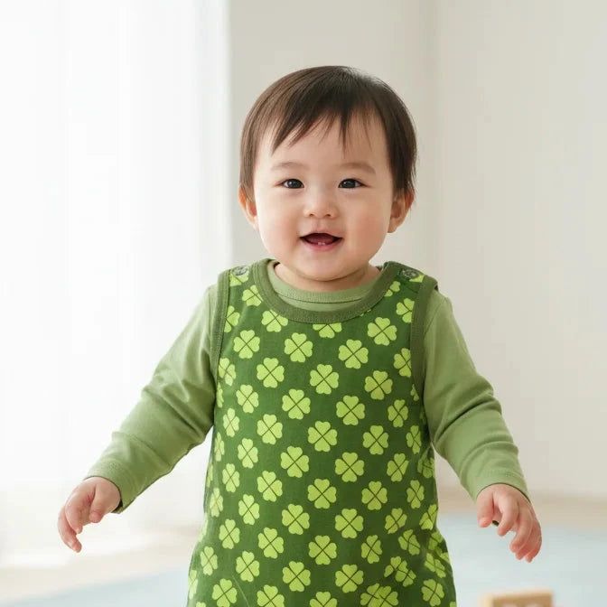 Baby wearing a green outfit with a clover pattern on a light background
