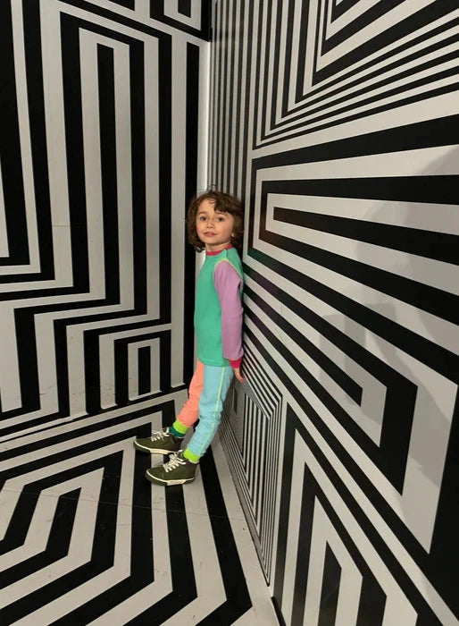 Child standing in a room with black and white striped walls