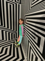 Child standing in a room with black and white striped walls