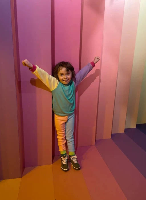 Child standing in a colorful room with pink and purple walls