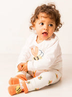Child wearing a white onesie with bunny design on a light background