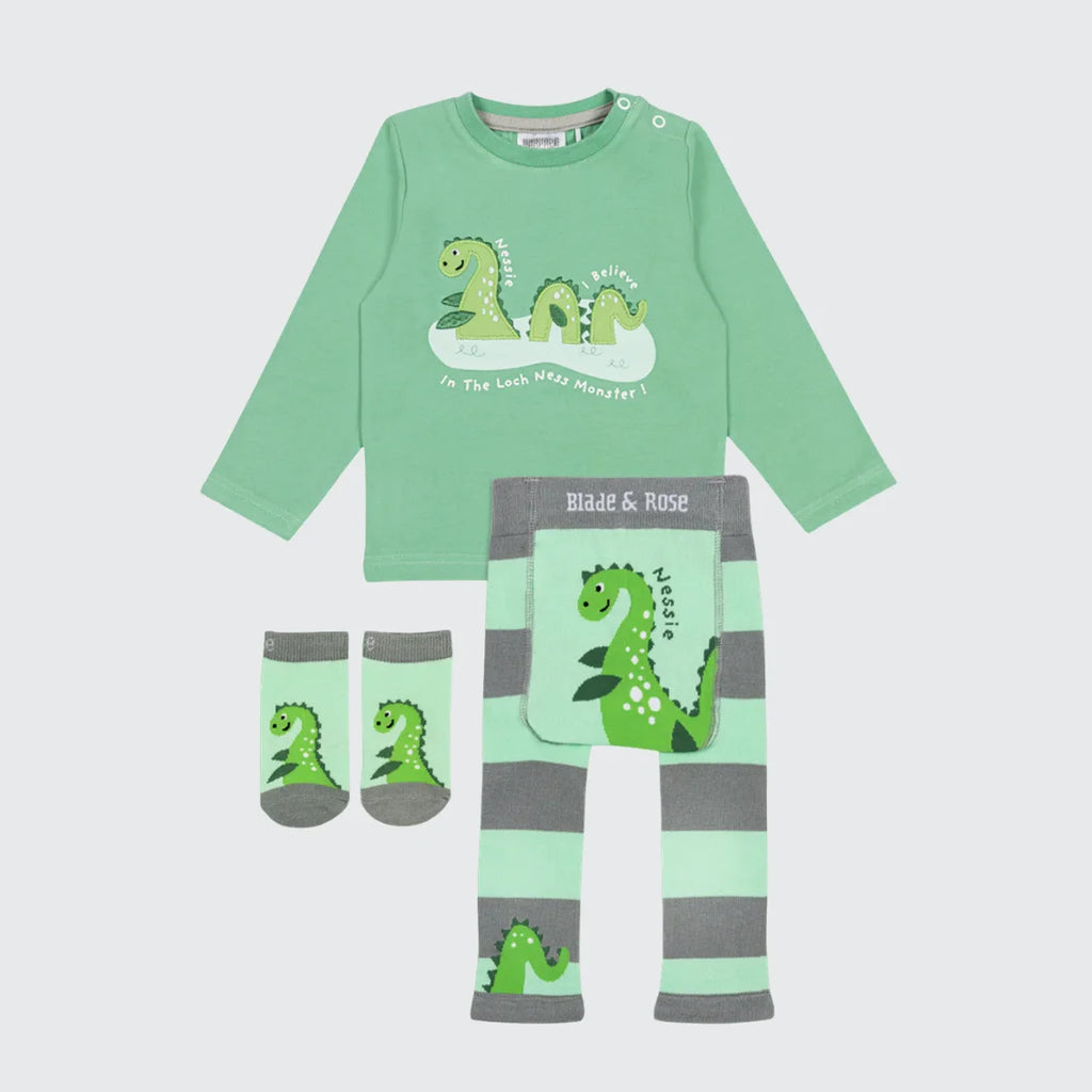 Children's outfit set with green long-sleeve shirt, striped pants, socks, and pouch featuring dinosaur designs on a light gray background.