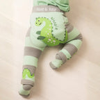 Green and gray striped baby leggings with dinosaur design on a beige background