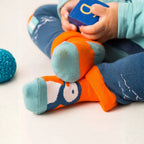Child wearing colorful socks with cartoon design, sitting on a white surface.