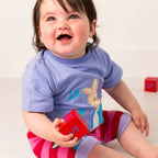 Child wearing a blue shirt with a cartoon character, holding a red box, on a white background