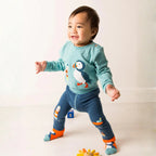 Child wearing a blue sweater with a penguin design and matching pants on a white background