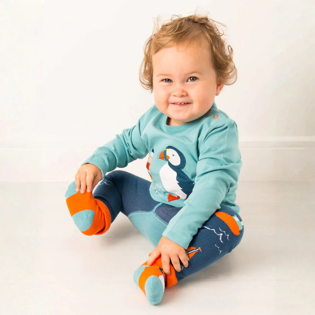 Child wearing a blue penguin-themed outfit with orange shoes on a white background