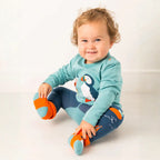 Child wearing a blue penguin-themed outfit with orange shoes on a white background