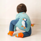 Child wearing a blue penguin-themed outfit with a visible brand name on a light background
