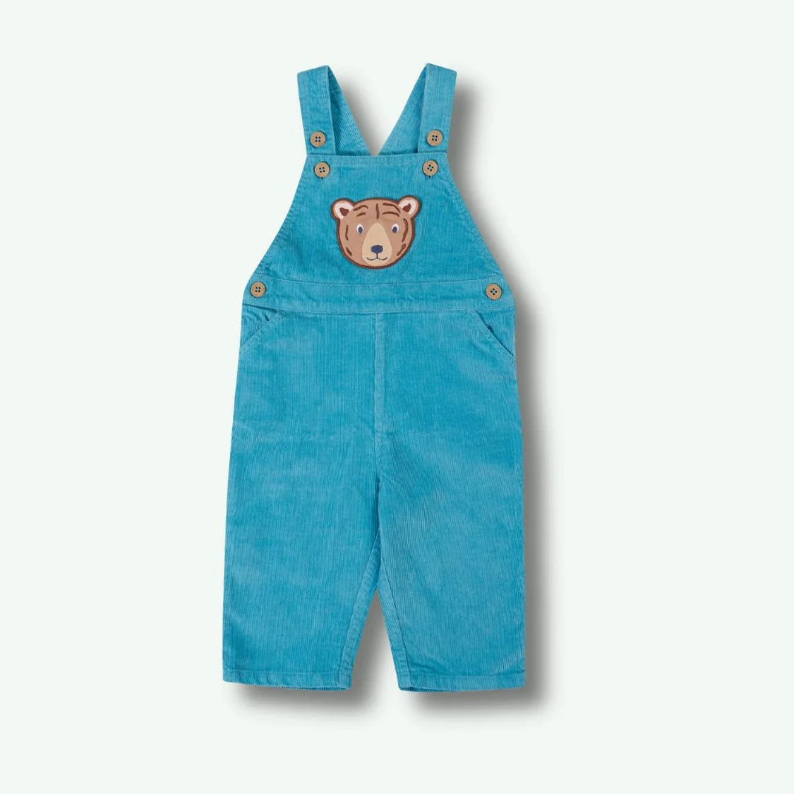 Blue denim overalls with a bear patch on a white background