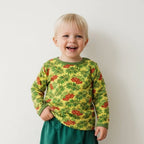 Child wearing a yellow long-sleeve shirt with red and green pattern against a plain background