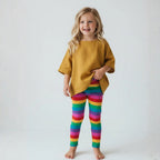 Child wearing a mustard yellow top and colorful striped leggings on a white background