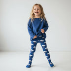 Child wearing a blue outfit with airplane pattern on a white background