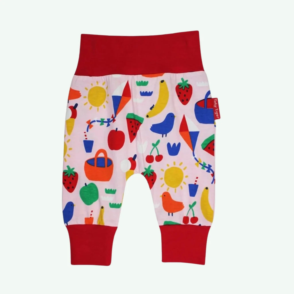 Colorful children's pants with a pattern of fruits, vegetables, and animals on a white background.