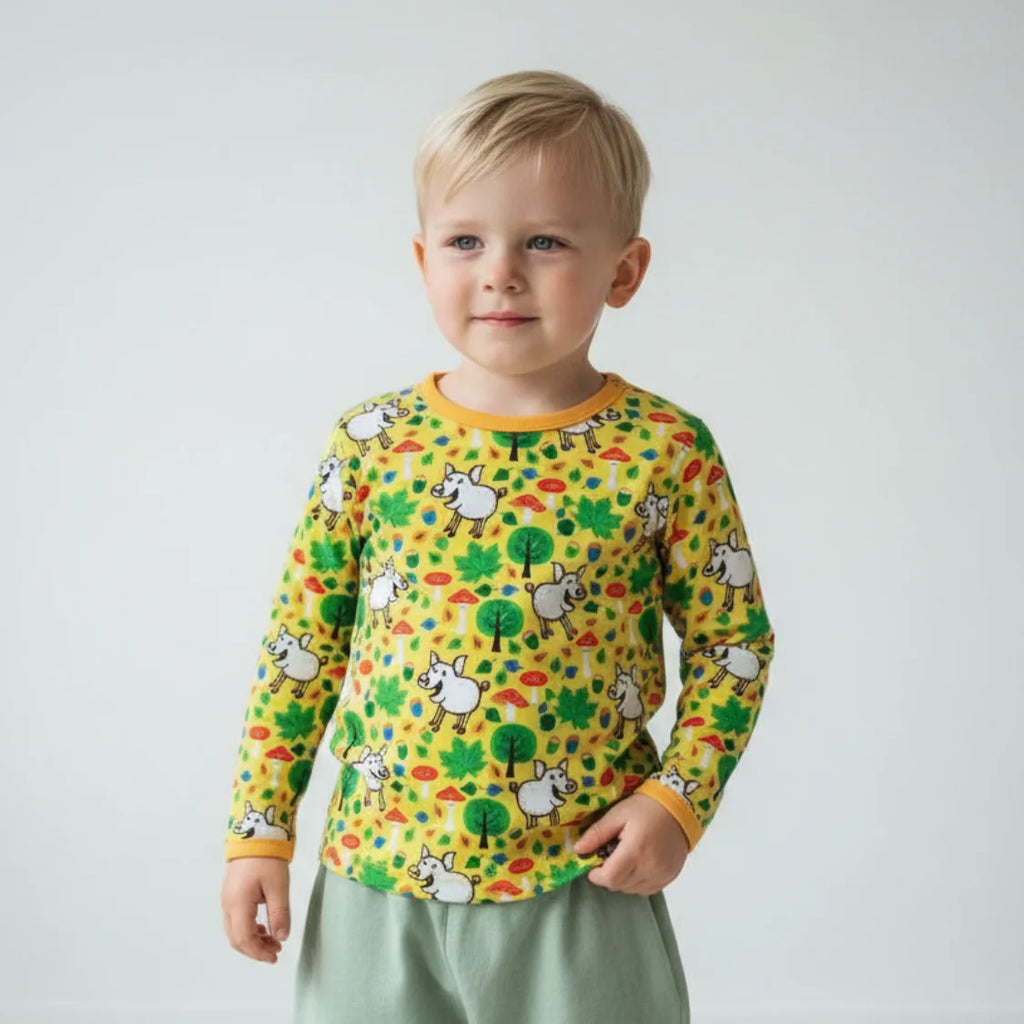 Child wearing a colorful long-sleeve shirt with animal patterns on a plain background