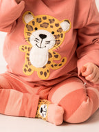 Child wearing a pink outfit with a leopard appliqué on a light background