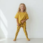 Child wearing a yellow outfit with patterned leggings on a white background