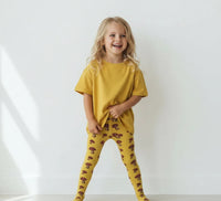 Child wearing a yellow outfit with patterned leggings on a white background