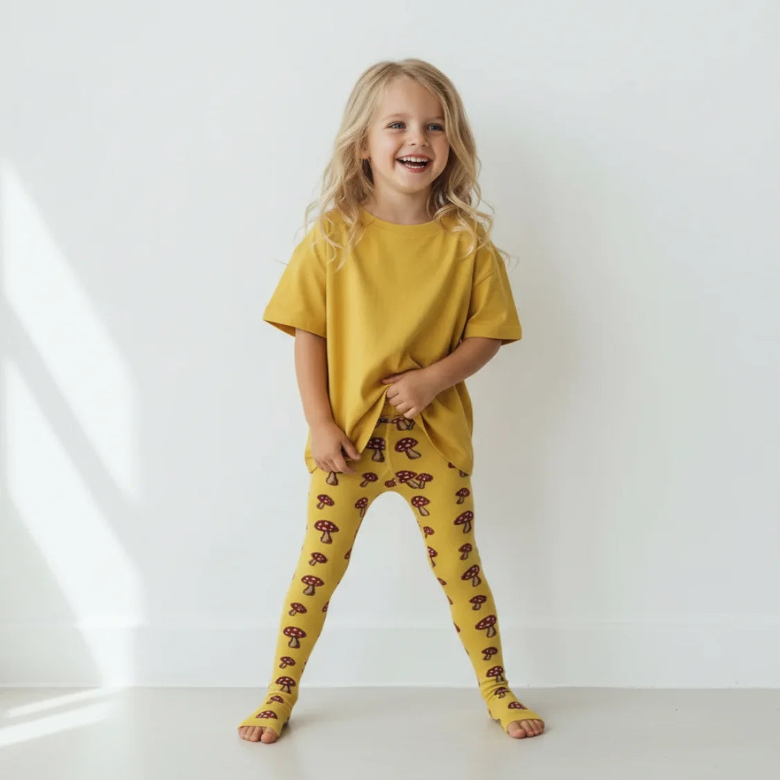 Child wearing a yellow outfit with patterned leggings on a white background