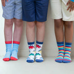 Three pairs of legs wearing colorful socks with different designs on a plain background