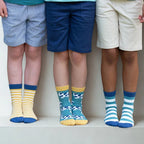 Three children wearing colorful socks with shorts on a white background