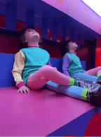 Two children sitting on a colorful geometric structure