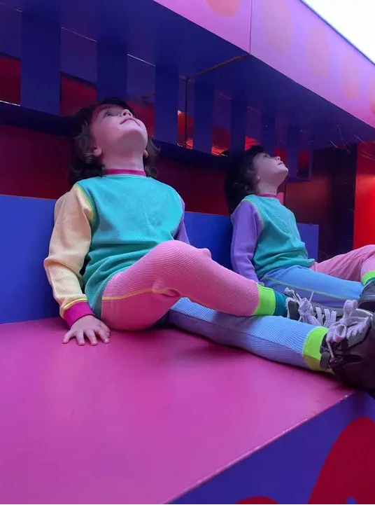 Two children sitting on a colorful geometric structure